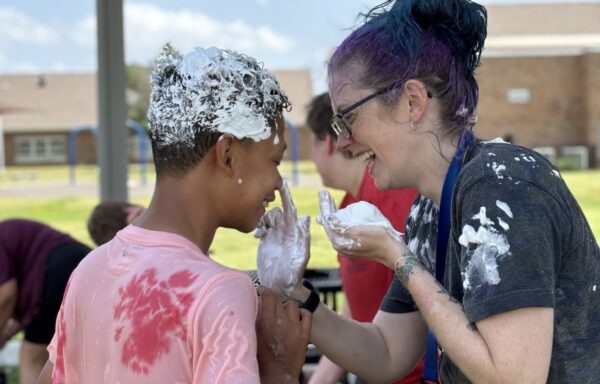 Heartspring direct support professional and student play with shaving cream during a Sunday Funday event.